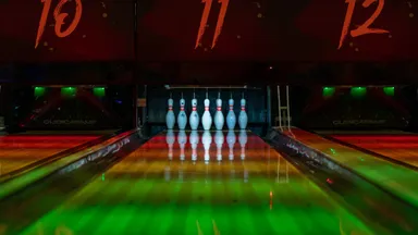 A dimly lit bowling alley with lanes receding into the dark