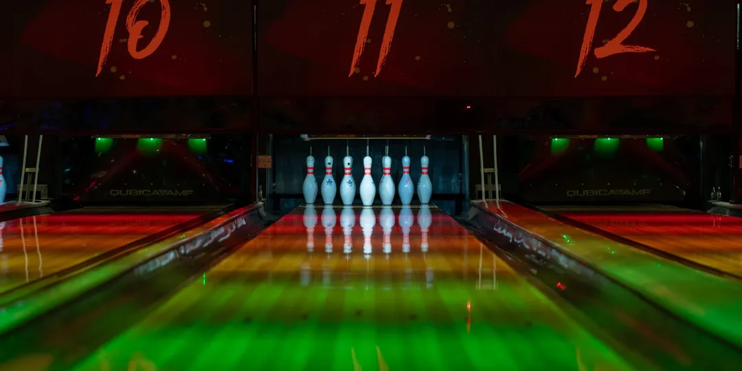 A dimly lit bowling alley with lanes receding into the dark