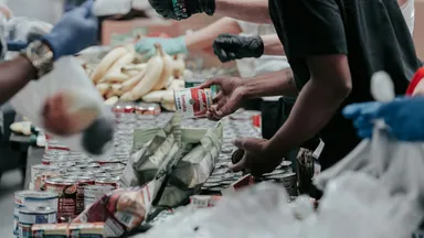 Gloved hands sorting donated food into bags at a distribution point
