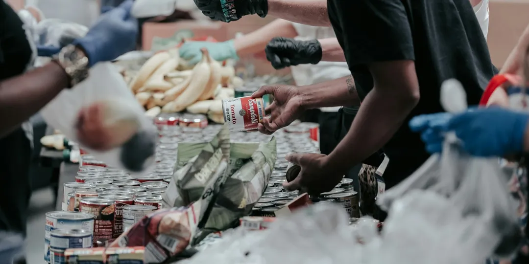 Gloved hands sorting donated food into bags at a distribution point