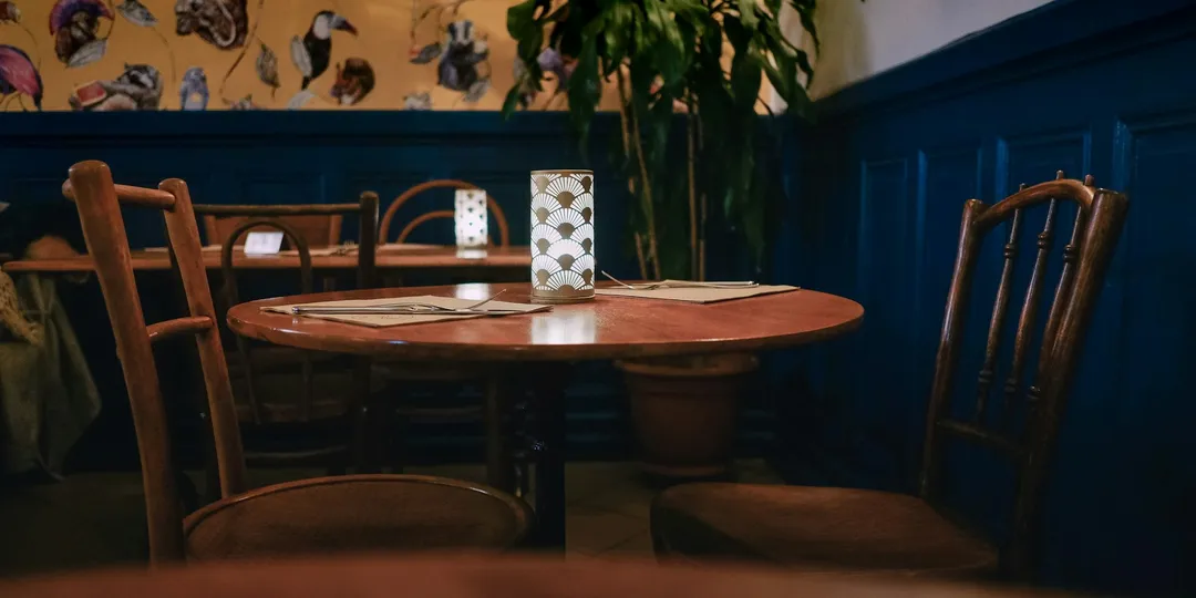 An empty round table with chairs pushed in, in a quiet restaurant