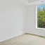 An empty white room with bare floorboards and a large window