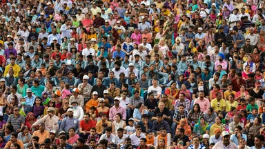 A densely packed crowd of thousands seated at an outdoor gathering in India