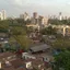 Dense low-rise housing in Dharavi, Mumbai, with high-rise blocks on the skyline behind