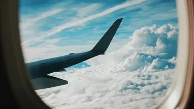 An aircraft wing above a patchwork of green fields, roads and small settlements