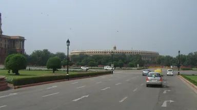 A broad road through New Delhi's government district with the Indian Parliament in the distance