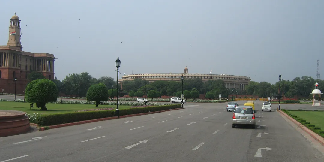 A broad road through New Delhi's government district with the Indian Parliament in the distance