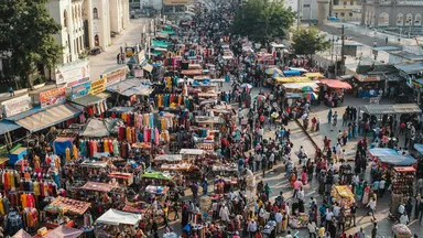 An aerial view of a dense Indian market street packed with stalls and people