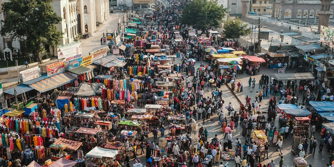 An aerial view of a dense Indian market street packed with stalls and people