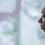 A person in profile looking out through a rain-streaked window