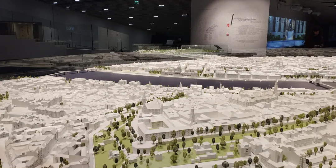 An architectural scale model of a city laid out under gallery lighting