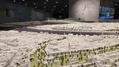 An architectural scale model of a city laid out under gallery lighting