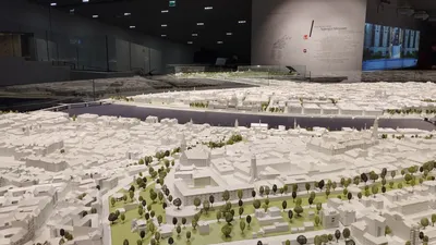 An architectural scale model of a city laid out under gallery lighting