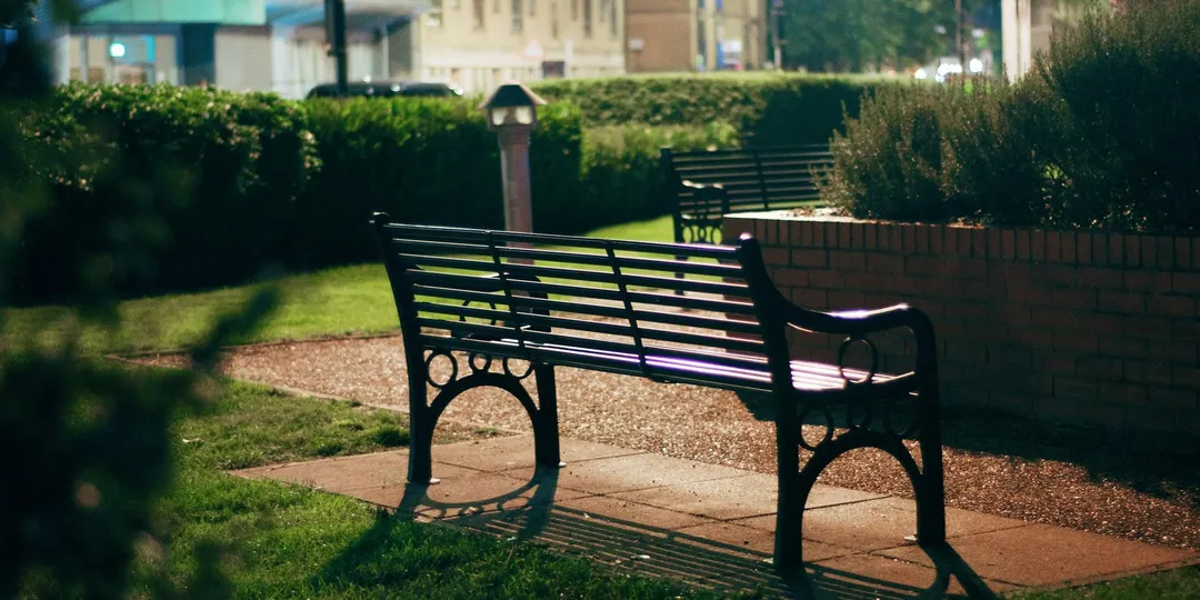 Two empty park benches in low evening light