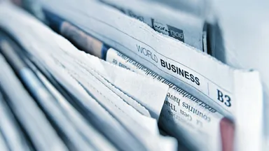 A tightly stacked row of folded newspapers seen edge-on