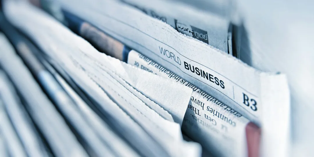 A tightly stacked row of folded newspapers seen edge-on