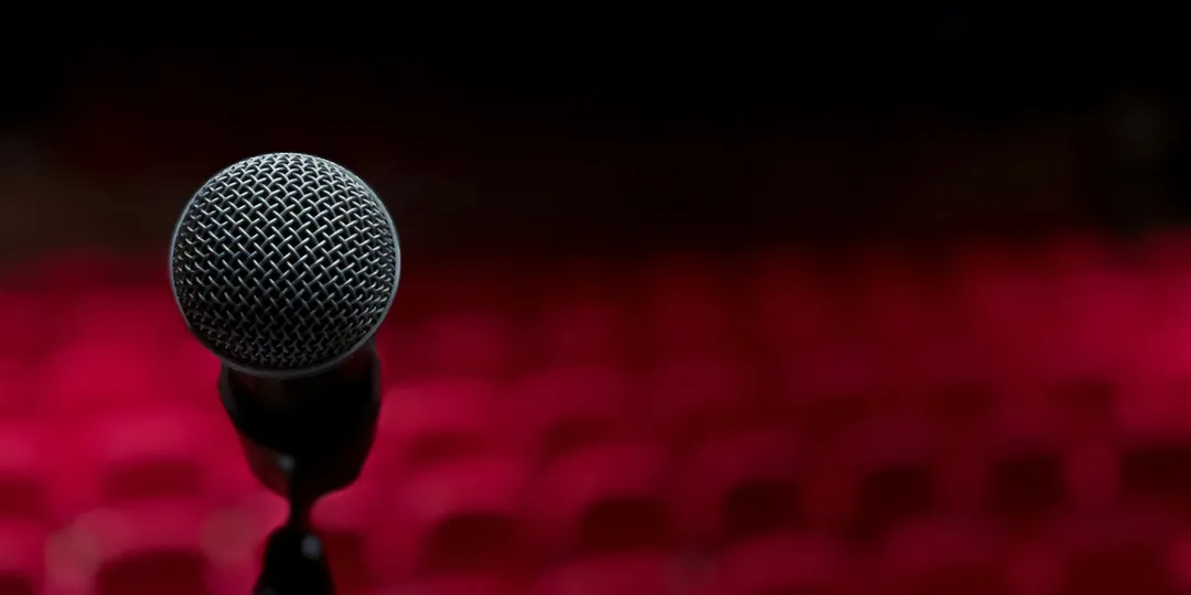 A microphone on a stand before rows of empty red theatre seats