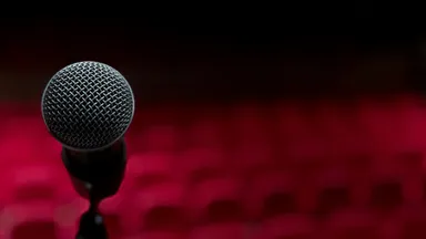 A microphone on a stand before rows of empty red theatre seats
