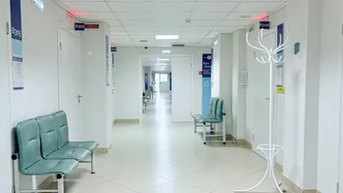 An empty hospital corridor lined with benches and closed doors