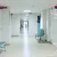 An empty hospital corridor lined with benches and closed doors