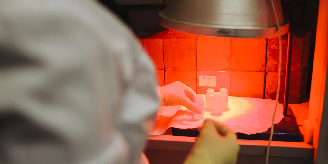 A laboratory scientist handling samples under red light