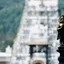 A small gilded deity figure in focus with a temple gopuram blurred behind