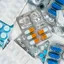 Blister packs of assorted pills and capsules scattered across a surface