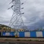 A high-voltage transmission tower rising above an electrical substation
