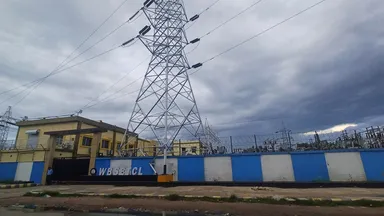 A high-voltage transmission tower rising above an electrical substation