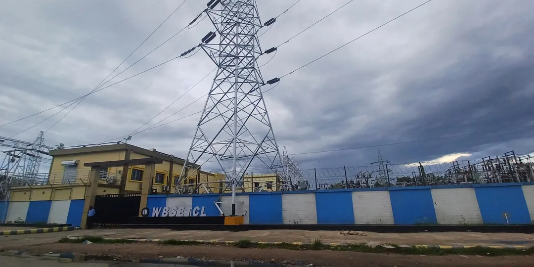 A high-voltage transmission tower rising above an electrical substation