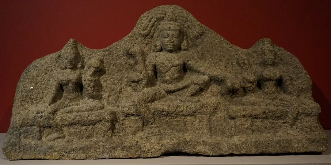A carved stone panel of the Tamil guardian deity Aiyanar flanked by his two consorts and attendant figures