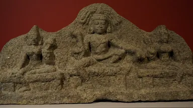 A carved stone panel of the Tamil guardian deity Aiyanar flanked by his two consorts and attendant figures