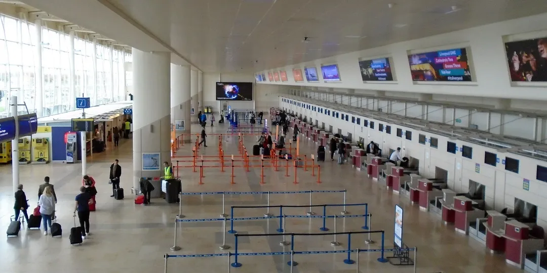 An airport departure concourse with empty queue barriers leading to check-in desks