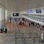 An airport departure concourse with empty queue barriers leading to check-in desks