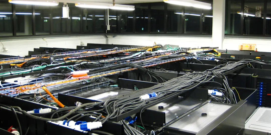 Rows of computer equipment and dense cabling in a server room