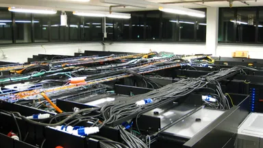 Rows of computer equipment and dense cabling in a server room