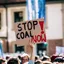 A protester holds a large Stop Coal Now sign above a gathered crowd
