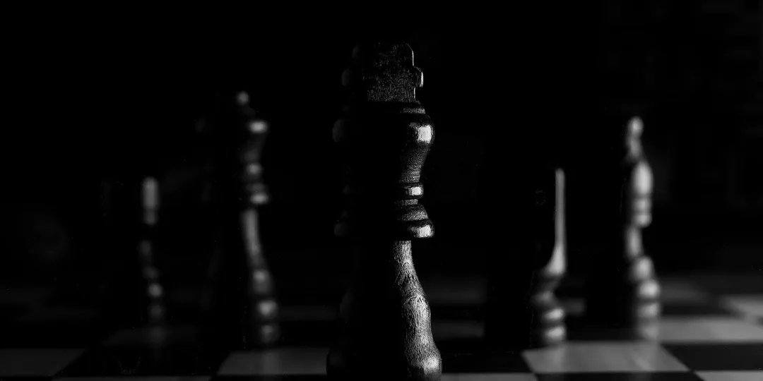 Chess pieces on a board in dramatic low light