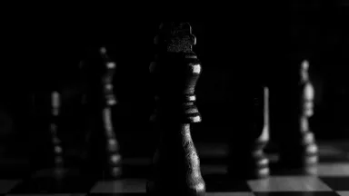 Chess pieces on a board in dramatic low light