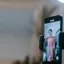 A smartphone mounted on a tripod, the person it is filming visible only on its screen