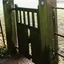 An old wooden gate set into a weathered metal fence in the countryside