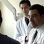 A physician consulting with a patient while another physician takes notes