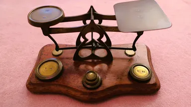 An old balance scale and a row of brass weights