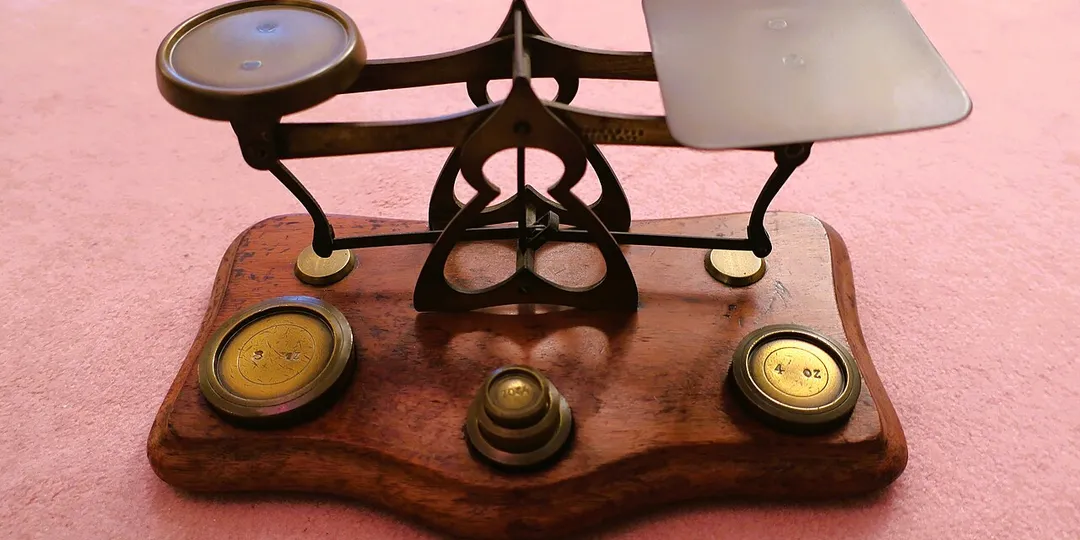 An old balance scale and a row of brass weights