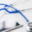 A stethoscope and a smartphone lying side by side on a white surface